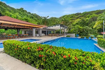 a pool at a resort with tables and chairs at Bahia Pez Vela Resort in Ocotal