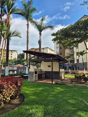 a park with palm trees and a building at Family getaway, pool, beach and surf in Jacó
