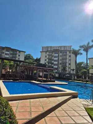 a large swimming pool with buildings in the background at Family getaway, pool, beach and surf in Jacó