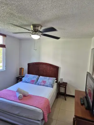 a bedroom with a bed with a ceiling fan at Family getaway, pool, beach and surf in Jacó