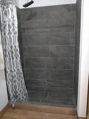 a bathroom with a shower with a stone wall at Selva Linda Lodge jungle wildlife vue and birdwatching in Quepos