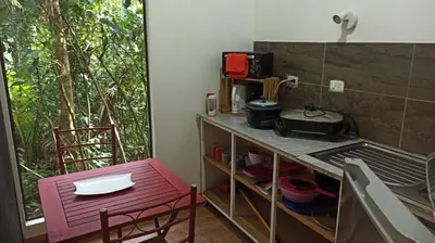a small kitchen with a table and a red stool at Selva Linda Lodge jungle wildlife vue and birdwatching in Quepos