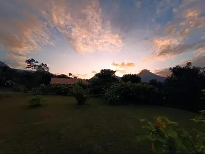 a sunset over a yard with a house and trees at Cabaña Rural Ave del Paraíso in Fortuna