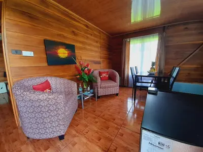 a living room with two chairs and a tv at Cabaña Rural Ave del Paraíso in Fortuna