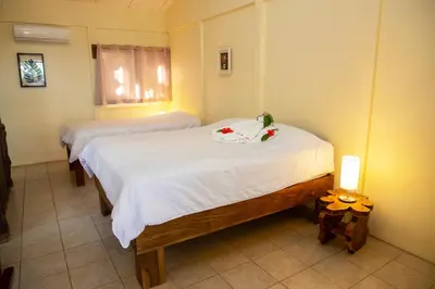 a bedroom with two beds with white sheets and flowers at Jungle Lodge at Wild Sun Rescue Center in Cabuya