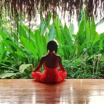 a woman in a red dress sitting on a wooden floor at Jungle Lodge at Wild Sun Rescue Center in Cabuya