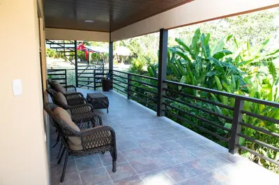 a screened porch with chairs and a table at Jungle Lodge at Wild Sun Rescue Center in Cabuya
