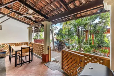 a porch with a table and chairs and trees at Colorful & Private 2-Bedroom Condo Just a Short Walk from the Beach in Coco
