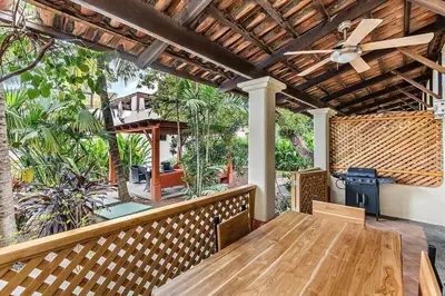 a porch with a wooden table and a ceiling fan at Colorful & Private 2-Bedroom Condo Just a Short Walk from the Beach in Coco