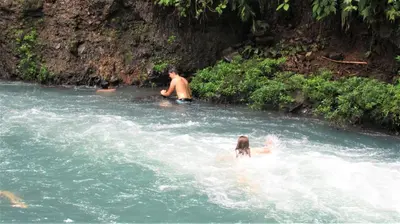 a group of people swimming in a river at Posada Río Celeste La Amistad in Rio Celeste