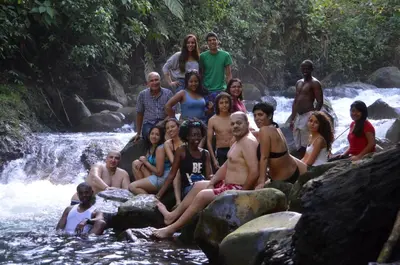 a group of people sitting on rocks in a river at Posada Río Celeste La Amistad in Rio Celeste