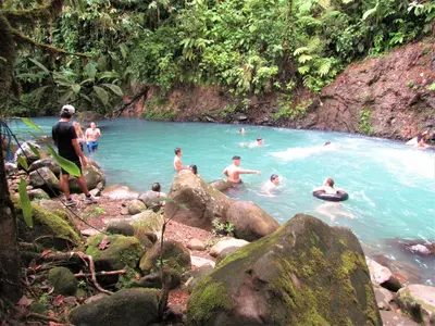 a group of people swimming in a pool of water at Posada Río Celeste La Amistad in Rio Celeste