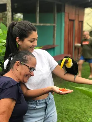 a woman standing next to a woman with a bird on her arm at Posada Río Celeste La Amistad in Rio Celeste