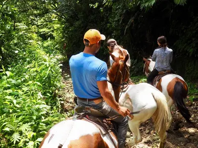 a group of people riding horses on a trail at Arenal Paraiso Resort Spa & Thermo Mineral Hot Springs in Fortuna
