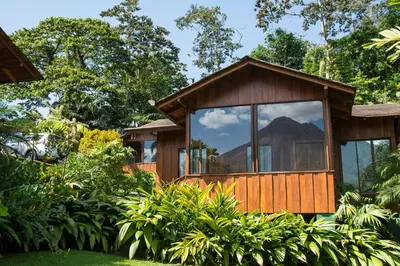 a tree house with a mountain reflection in the window at Arenal Paraiso Resort Spa & Thermo Mineral Hot Springs in Fortuna