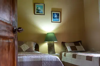 a bedroom with two beds and a green lamp at Calas Lodge in Bajos del Toro