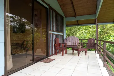a screened in porch with two chairs and a table at Calas Lodge in Bajos del Toro