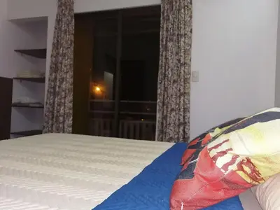 a bedroom with a bed and a window with curtains at Aptos Casa Caribe, habitaciones privadas en aptos compartidos & aptos completos con auto entrada in Puerto Limón