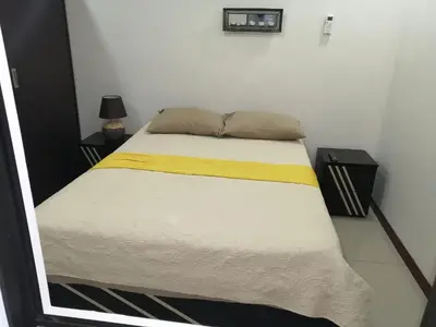 a bedroom with a bed with a yellow and white blanket at Aptos Casa Caribe, habitaciones privadas en aptos compartidos & aptos completos con auto entrada in Puerto Limón