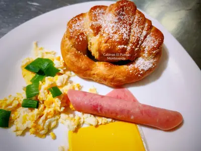 a plate of food with a sausage and a donut at Cabinas El Pueblo B&B Monteverde in Monteverde Costa Rica