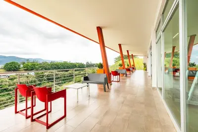 a room with red chairs and tables on a balcony at Boho Chic, Apart- condo cerca de SJO Intl airport in Barrial