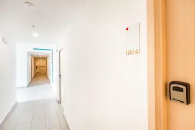 a hallway with a white wall and a door with a sign on it at Boho Chic, Apart- condo cerca de SJO Intl airport in Barrial