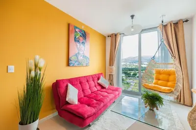 a red couch in a living room with a window at Boho Chic, Apart- condo cerca de SJO Intl airport in Barrial