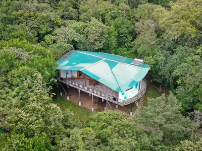 a house with a blue roof in the middle of a forest at Moon Wonders Vacation House in Monteverde Costa Rica