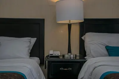 a bedroom with two beds and a lamp on a night stand at Hotel Colonial in San José
