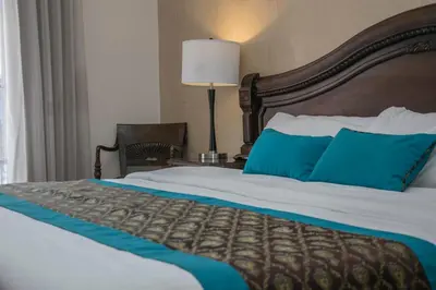 a large bed in a hotel room with blue pillows at Hotel Colonial in San José