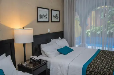 a hotel room with a bed with a lamp and a phone at Hotel Colonial in San José