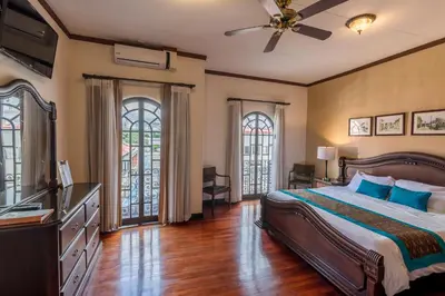 a bedroom with a bed and a dresser and two windows at Hotel Colonial in San José