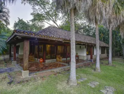a house with a porch and two palm trees at Hacienda La Pacífica Eco-Lodge in Cañas