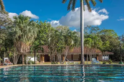 a swimming pool in front of a house with palm trees at Hacienda La Pacífica Eco-Lodge in Cañas