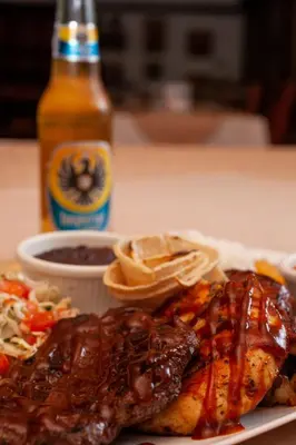 a plate of food with meat and a bottle of beer at Hacienda La Pacífica Eco-Lodge in Cañas