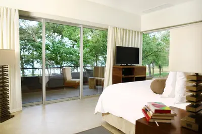 a bedroom with a bed and a tv and a balcony at El Mangroove Papagayo, Autograph Collection in Papagayo, Guanacaste