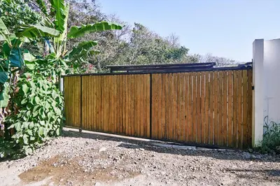 a wooden fence in a yard next to a tree at Villa Koi ~ Brand NEW Villa ~ 2 Bedrooms with Pool in Carmen