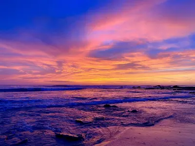 a sunset on a beach with the ocean at Santeria Lodge in Santa Teresa Beach