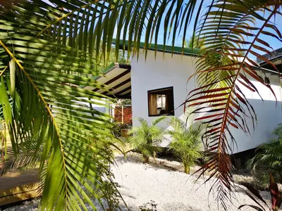 a white house with palm trees in front of it at Santeria Lodge in Santa Teresa Beach