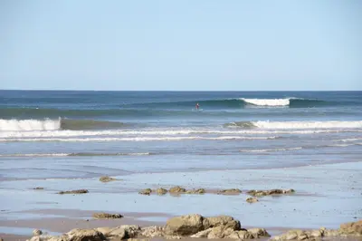 a beach with waves and people in the ocean at Santeria Lodge in Santa Teresa Beach