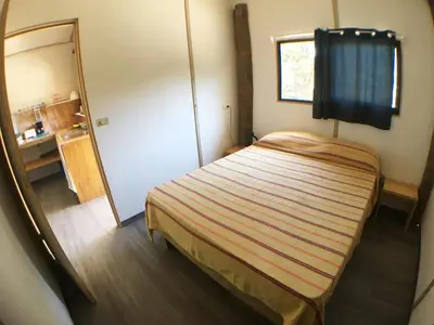 a small bedroom with a bed and a mirror at Santeria Lodge in Santa Teresa Beach