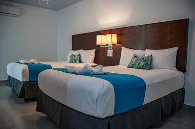 two large beds in a hotel room with blue and white sheets at HOTEL MARINO BALLENA in Uvita