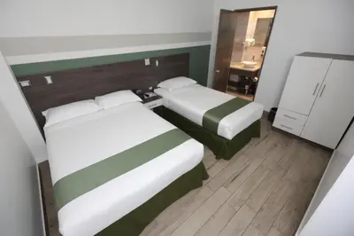 two beds in a small room with a bathroom at Hotel Cultura Plaza in San José