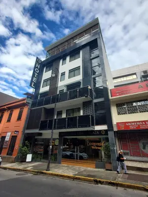 a man walking past a building on a street at Hotel Cultura Plaza in San José