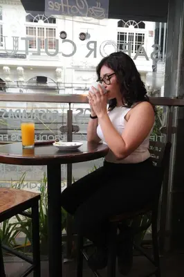 a woman sitting at a table drinking from a cup at Hotel Cultura Plaza in San José