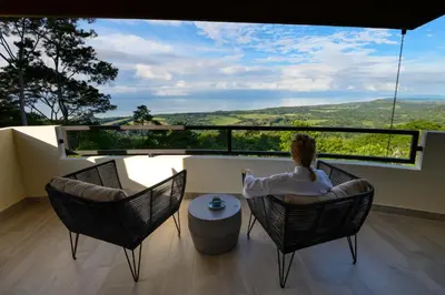 a woman sitting in a chair on a balcony at Lapazul Boutique Hotel in Savegre
