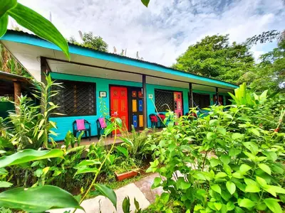 a house with colorful doors and chairs in a yard at Cabinas Tortuguero in Tortuguero