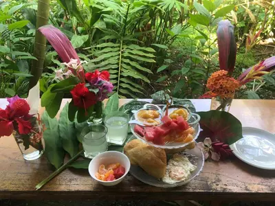a table with plates of food and drinks and flowers at Cabinas Tortuguero in Tortuguero