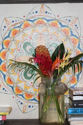 a vase with flowers in front of a wall at Cabinas Tortuguero in Tortuguero