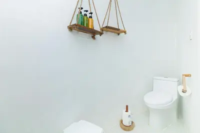 a white bathroom with a toilet and some bottles at Igloo Beach Lodge in Manuel Antonio